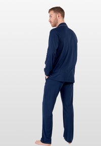 Conjunto de pijama azul marino hecho de material suave, con mangas largas y pantalones de corte relajado. Diseño liso sin patrones o acentos distintivos.