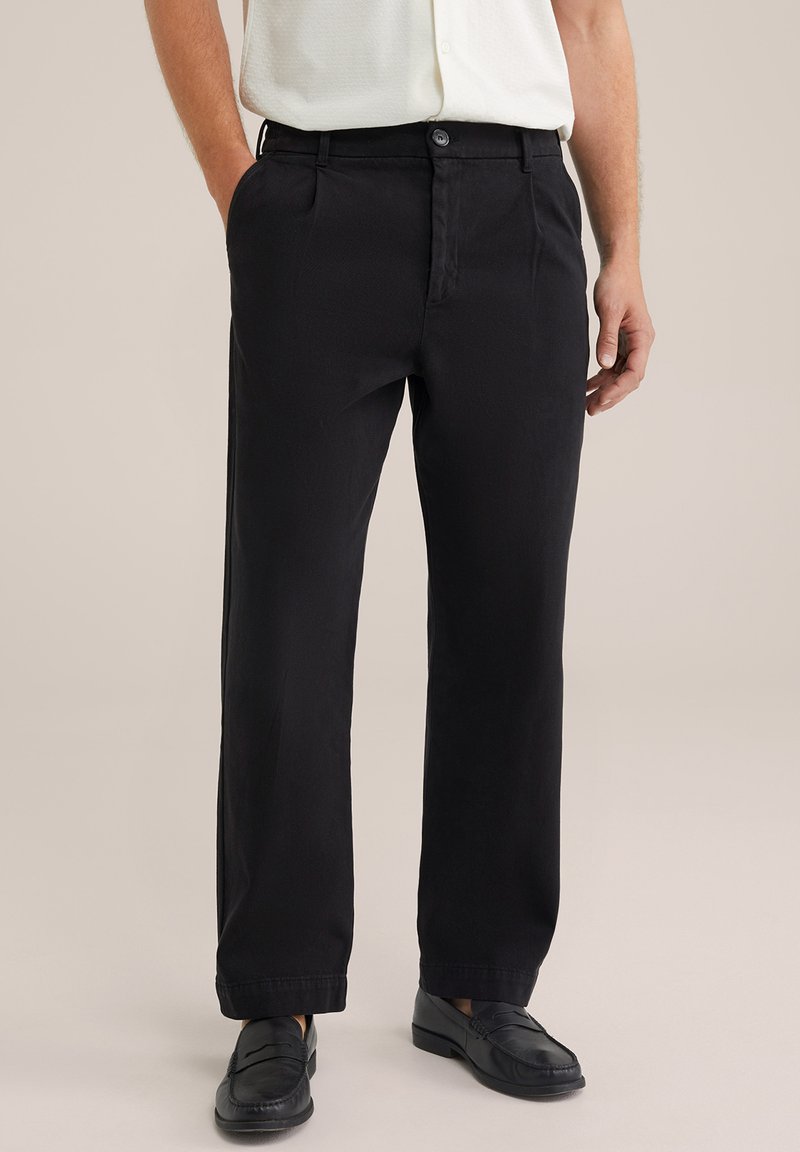 Los pantalones de algodón negros presentan un diseño de pierna recta, cierre de botón y bolsillos laterales, con una textura suave y mate.