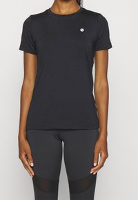 Camisa negra de manga corta hecha de un tejido suave y elástico. Presenta un cuello redondo y un pequeño logo en el pecho. Diseño ajustado.
