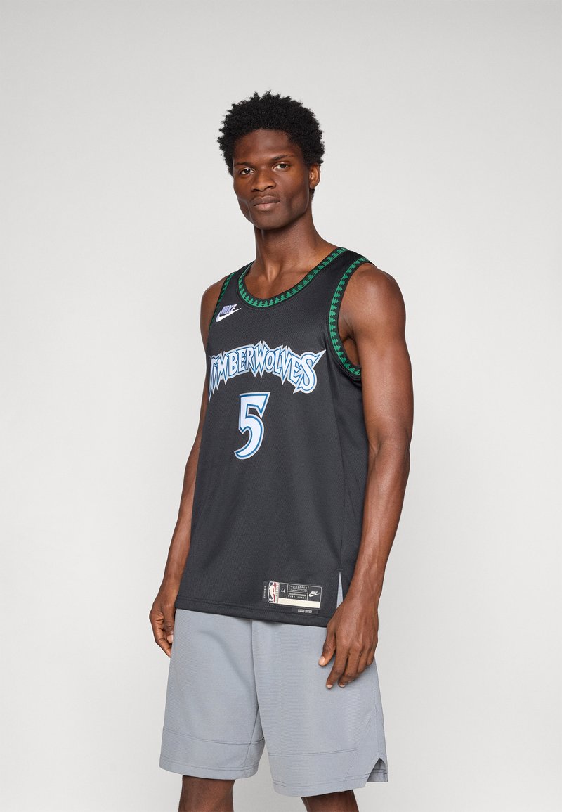 Camisola de basquetebol preta com gráfico "Timberwolves" em azul claro, número 5, e um destaque verde no colarinho. Combinada com calções cinzentos.
