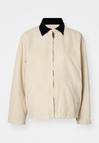 Beżowa kurtka płócienna z czarnym kołnierzem z sztruksu, przednim zamkiem błyskawicznym i dwoma bocznymi kieszeniami. Projekt jest casualowy i nieustrukturyzowany.