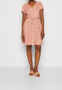 Robe portefeuille fleurie rouge et blanche, avec un col en V, des manches courtes à volants, une ceinture à nouer et une jupe mi-longue à ourlet évasé.