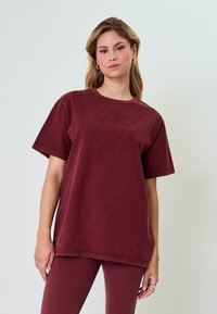 Bordo per didelį T-shirt'ą, pagamintą iš švelnaus medvilnės, su apvaliu kaklu ir trumpomis rankovėmis, dėvimas su atitinkančiomis prigludusiomis leginsomis.