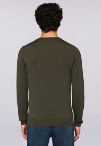 Olivově zelený svetr s dlouhými rukávy, kulatým výstřihem, žebrovanými manžetami a spodním lemem. Textura vypadá hladce a má klasický střih.