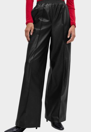 Schwarze weite Hosen aus Kunstleder mit elastischem Bund, vertikalen Nähten für Struktur und glatter, glänzender Textur.