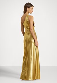 Aukso spalvos metalinė vakarinė suknelė su aptempta forma, viena petneša, raukiniais ir ilgu, laisvai krintančiu sijonu, siekiančiu grindis. Lygus faktūra.