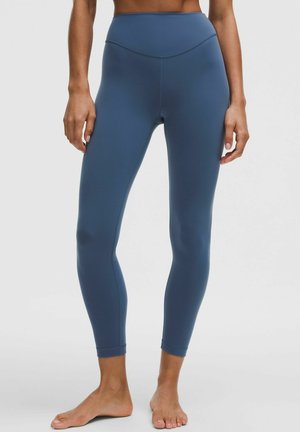 Højtaljede leggings i en dyb blå farve, lavet af strækbart materiale, med en glat tekstur og tætsiddende design. Ingen synlige mønstre eller hardware.