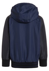 Granatowa kurtka z kapturem z elastycznymi mankietami i dołem. Wykonana z gładkiego, lekkiego materiału z kontrastującymi czarnymi rękawami. Prosty design.