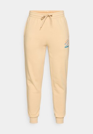 Gai bēšas jogger bikses, izgatavotas no mīksta kokvilnas maisījuma, ar elastīgu jostasvietu un auklu, sānu kabatām un logotipu uz augšstilba.