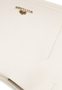 Witte gestructureerde leren handtas met een gouden logo, minimalistisch ontwerp en discreete stiksel details. Glad oppervlak met een gestructureerde vorm.