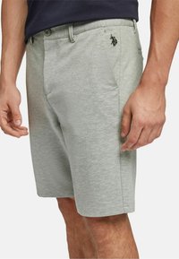 Light gray shorts made of a soft fabric, featuring a button closure, side pockets, and a small black logo on the left thigh.