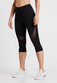 Czarne legginsy capri z wysokim stanem i przezroczystymi wstawkami po bokach. Wykonane z elastycznego materiału dla komfortu i swobody ruchów.