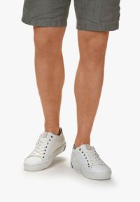 White lace-up sneakers with a smooth leather upper, rubber sole, and minimalistic design; feature blue accents on the heel.