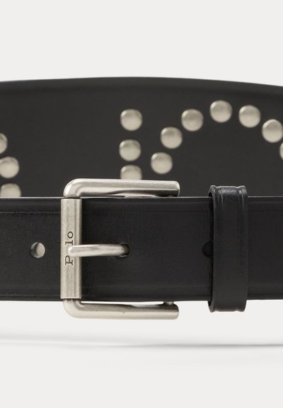 Μαύρη δερμάτινη ζώνη με ασημένια μεταλλική αγκράφα χαραγμένη με τη λέξη "Polo" και στρογγυλές ασημένιες τρούκς που σχηματίζουν ένα μοτίβο κατά μήκος του ιμάντα.