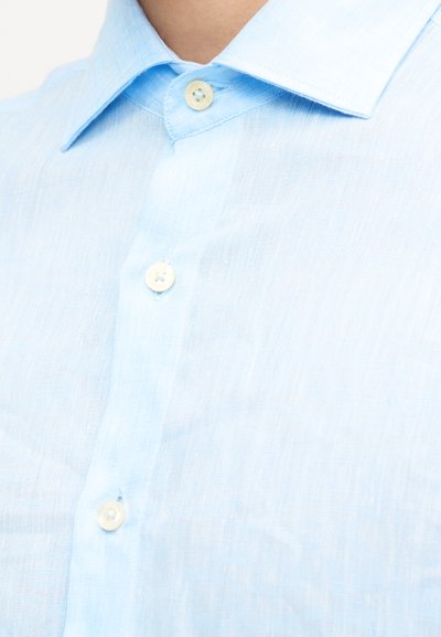 Φωτεινό γαλάζιο λινό πουκάμισο με γιακά με κουμπιά και τρία ορατά λευκά κουμπιά στο πάνω μέρος του στήθους και του λαιμού ενός ατόμου.