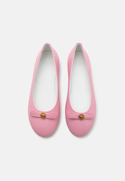 Ballerine rosa realizzate in materiale morbido, con punta rotonda, un piccolo dettaglio a fiocco e un'emblema dorato sul davanti.