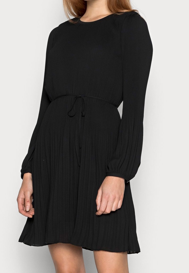 Czarna sukienka plisowana z długimi rękawami, okrągłym dekoltem i regulowanym w pasie. Miękka tkanina o fakturowanym wykończeniu. Sukienka o długości midi.