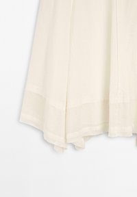 Tissu léger couleur crème avec un ourlet large cousu et de doux plis sur le bord inférieur.