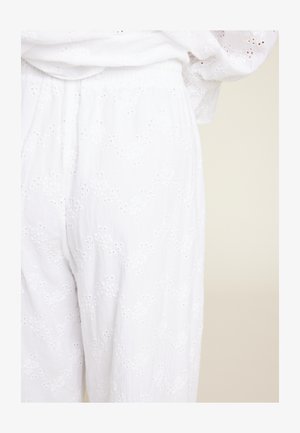 Hvite broderte bukser laget av lett stoff. Har øyelette mønstre og elastisk midje. Glatt tekstur med løs passform.