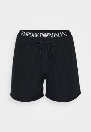 Shorts de bain noirs avec une taille élastique à cordon, arborant un logo blanc "Emporio Armani" sur la ceinture. Tissu lisse, atteignant le milieu de la cuisse.
