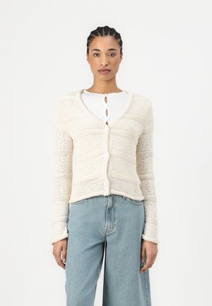 Strikket cardigan i off-white, med V-hals, lange ermer og knappelukking. Teksturert mønster, kort lengde og ribbestrikket kant.