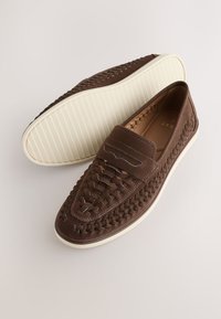 Chaussures en cuir tressé marron sans lacets avec semelles en caoutchouc blanc, style mocassins décontractés, vues de dessus et de dessous.