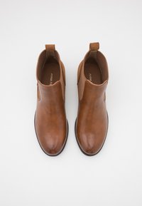 Bottines en cuir marron avec des panneaux élastiques sur les côtés, bout arrondi et languette au talon. Texture lisse et design minimaliste.