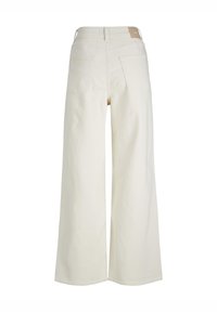 Jeans de perna larga, na cor creme, feitos de denim. Apresentam uma cintura alta, dois bolsos traseiros e uma pequena etiqueta de marca na cintura.