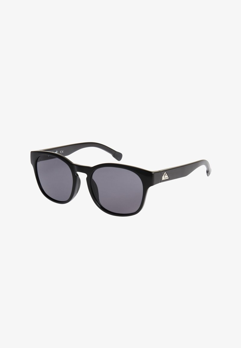 Lunettes de soleil rectangulaires noires avec des verres teintés foncés et un logo triangulaire argenté sur la branche, sur un fond blanc.