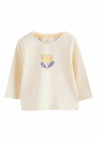 Camiseta de bebé de manga larga en color crema con un gráfico de un tulipán sonriente y el texto "hola sonrisas" centrado en la parte frontal, botones a presión en el hombro.