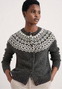 Siva volnena cardigan s krojem okroglih ramenskih šivov in belimi geometrijskimi vzorci, z gumbom za zapiranje, rebrastimi manšetami in strukturirano površino.