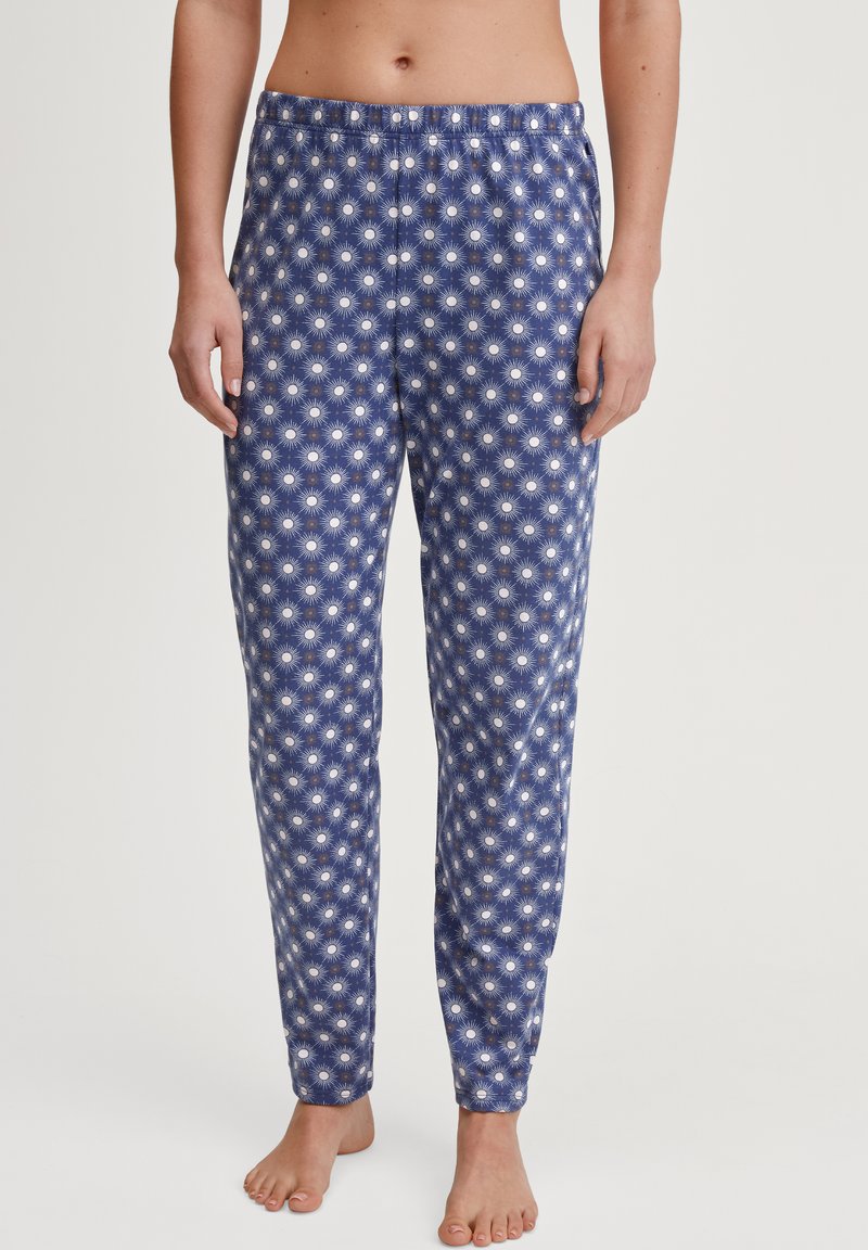 Blauwe pyjamabroek van zachte stof, met een zonnestraalpatroon in het wit. Ontspannen pasvorm met een elastische tailleband en taps toelopende benen.