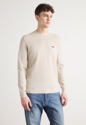 Beige gebreide trui met lange mouwen en een ronde halslijn, met het BOSS-logo op de borst. Het materiaal lijkt zacht te zijn, met een gladde textuur en een aangesloten pasvorm.