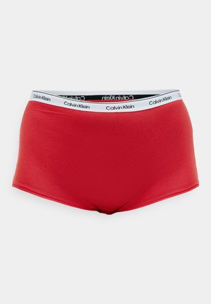 Calzoncillos de algodón rojo elástico con una amplia cinturilla blanca que presenta el logo de Calvin Klein en negro. Textura suave y diseño de altura media.