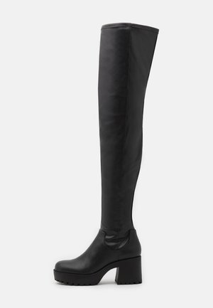 Botte noire cuissarde à talon haut avec semelle épaisse et talon bloc, texture en cuir lisse et bout arrondi.