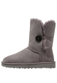 Stivale alla caviglia in suede grigio con fodera in pelliccia sintetica, punta rotonda, dettaglio in bottone laterale e suola in gomma testurizzata per una buona aderenza.