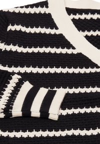 Cardigan a righe bianco e nero con un motivo a maglia testurizzata, dotato di scollo a V e polsini a coste a righe.