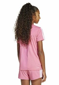 Camiseta deportiva rosa con rayas blancas en las mangas, combinada con pantalones cortos a juego. Textura suave, mangas cortas y un ajuste holgado.