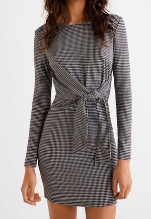 Robe à manches longues en pied-de-poule noir et blanc avec un nœud noué à la taille à l'avant, une silhouette ajustée et un col rond.