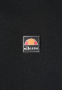 Black textile surface featuring a square logo with a gray border, orange and red semicircles above the word "ellesse" in white lettering.