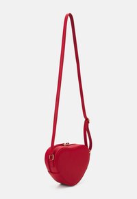 Rød, hjerteformet crossbody-taske lavet af glat læder med tyndt justerbart rem og gulddetaljer. Lynlåslukning på toppen.