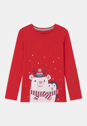 Rød langærmet børneskjorte med en hvid bjørn med gevir og et stribet tørklæde, der krammer en pingvin, omgivet af snefnug.