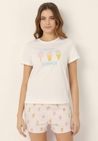 White cotton t-shirt features colorful ice cream and popsicle graphics with "Sweet Summer" text. Pink patterned shorts complement the top.