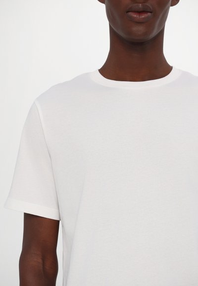 Weißes Baumwoll-T-Shirt mit rundem Ausschnitt und kurzen Ärmeln, mit glatter Textur und klassischem Schnitt. Keine sichtbaren Muster oder Akzente.