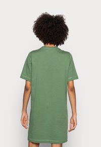 Zielona sukienka z bawełny w kształcie t-shirta, o luźnym kroju, z krótkimi rękawami i okrągłym dekoltem. Posiada gładką tkaninę i minimalne detale szwów.