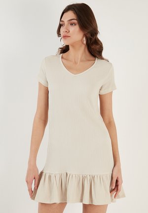 Short-sleeve, v-neck dress in light beige with a textured fabric and flared ruffle hem. Soft material with a relaxed fit.
