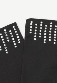 Černé návleky na nohy s řadou lesklých, průhledných rhinestones uspořádaných v svislých liniích podél horního okraje pro dekorativní efekt.