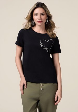 T-shirt en coton noir à manches courtes avec un design de cœur en strass sur le côté gauche. Associé à un pantalon olive avec des boutons décoratifs.