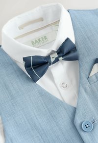 Weißes Hemd mit dunkelblauer Fliege mit Muster und hellblauem Weste mit passendem Knopf und Einstecktuch.