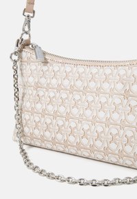 Pochette blanche texturée avec un motif tissé, dotée d'une chaîne en argent et d'une fermeture éclair. Le matériau semble durable et facile à nettoyer.